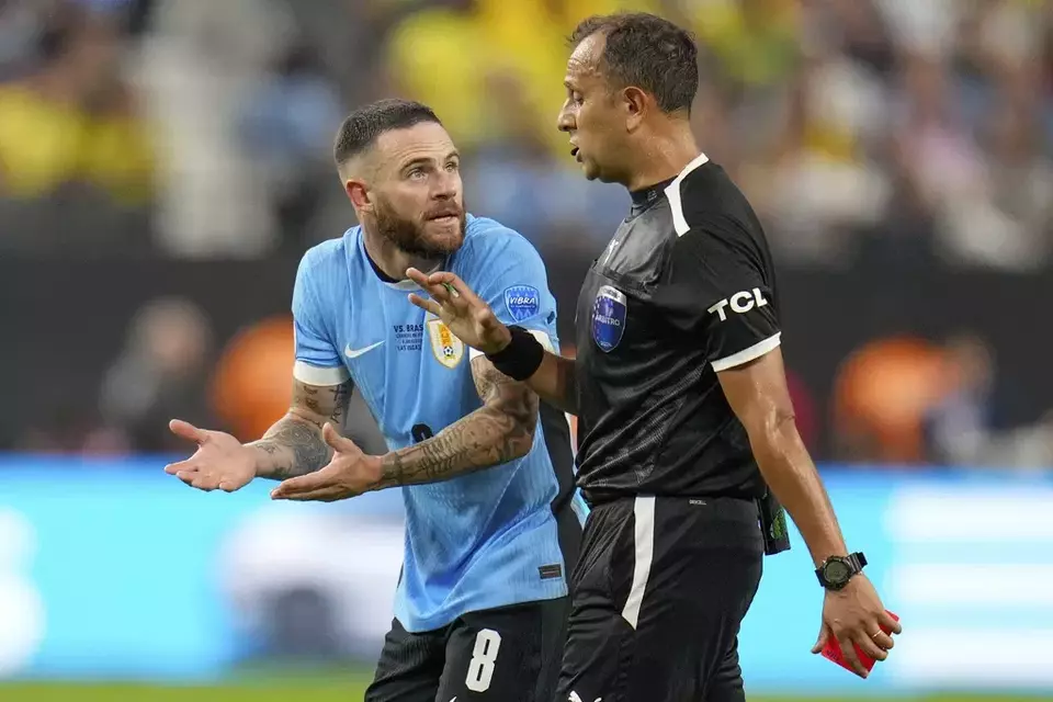 Bek Uruguay Nahitan Nandez memprotes keputusan wasit Dario Herrera setelah dia diganjar kartu merah saat melawan Brasil.